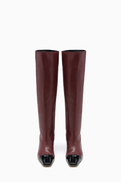 Bottes hautes en cuir de veau acajou, vue de face de la paire avec bout cap en vernis | Ulla Johnson